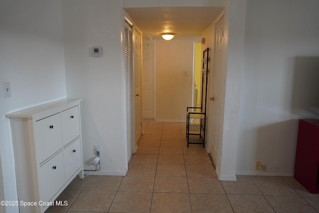 corridor with baseboards and light tile patterned flooring