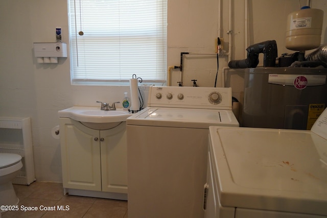 washroom featuring light tile patterned floors, washer and dryer, laundry area, and electric water heater