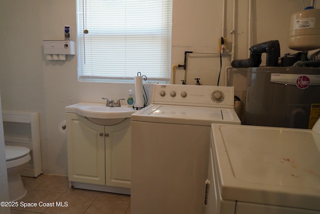 laundry room featuring water heater, washer and dryer, and light tile patterned floors