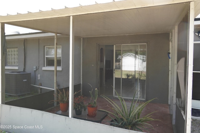view of exterior entry with central AC and stucco siding