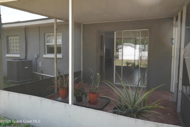 doorway to property featuring stucco siding and central AC unit