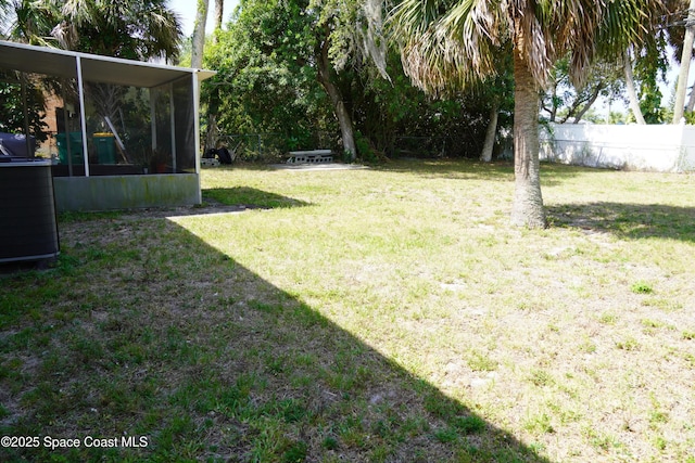 view of yard featuring central AC, fence, and a sunroom