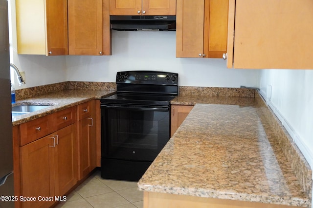 kitchen with a sink, under cabinet range hood, light tile patterned flooring, brown cabinetry, and black electric range oven