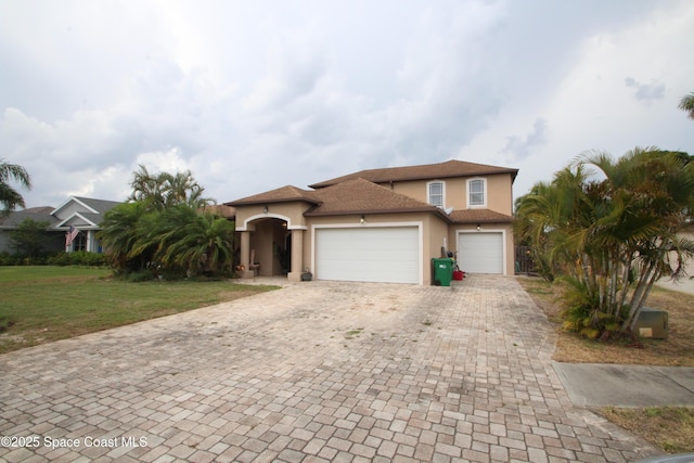 mediterranean / spanish-style home with stucco siding, an attached garage, decorative driveway, and a front yard