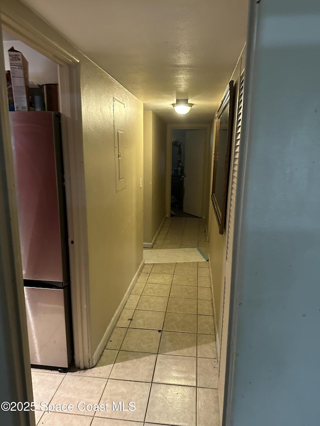 hallway featuring light tile patterned flooring and baseboards