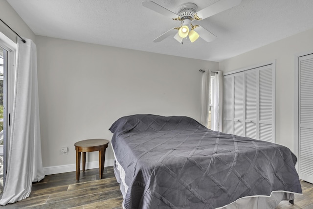 bedroom featuring wood finished floors, two closets, a ceiling fan, and baseboards