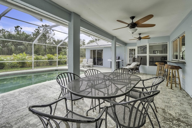 sunroom with outdoor dry bar, a ceiling fan, and outdoor dining space