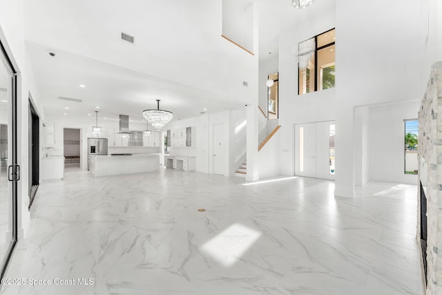 2355 N Riverside Dr, Indialantic, FL 32903 - unfurnished living room with marble finish floor, a towering ceiling, a chandelier, and stairway