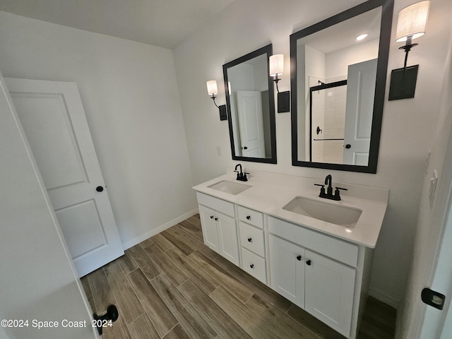 bathroom with wood finish floors, a sink, a shower stall, and baseboards