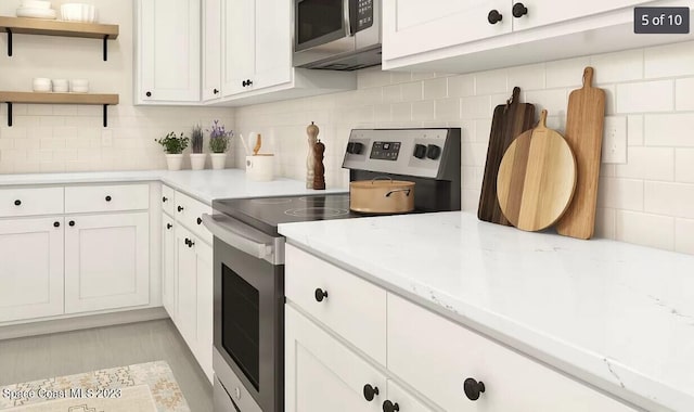 kitchen featuring white cabinetry, open shelves, appliances with stainless steel finishes, and decorative backsplash