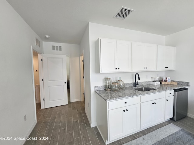 kitchen with visible vents, baseboards, wood finish floors, and a sink