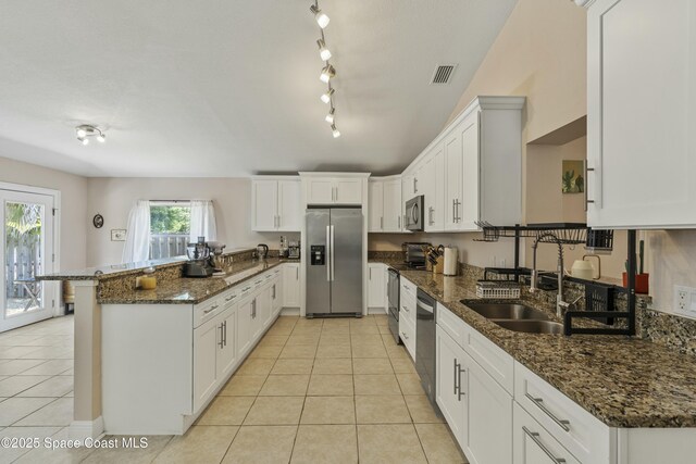 1044 Bernice Rd, Rockledge, FL 32955 - kitchen featuring a peninsula, dark stone counters, a sink, appliances with stainless steel finishes, and light tile patterned floors