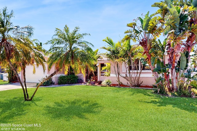 view of front of house with a front lawn, driveway, a garage, and stucco siding