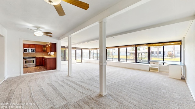 unfurnished living room featuring light colored carpet, ceiling fan, and plenty of natural light