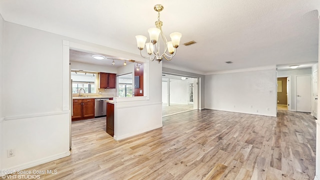 kitchen with stainless steel dishwasher, light countertops, an inviting chandelier, open floor plan, and light wood-type flooring