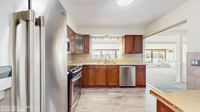 kitchen with stainless steel appliances, light countertops, brown cabinetry, and a sink