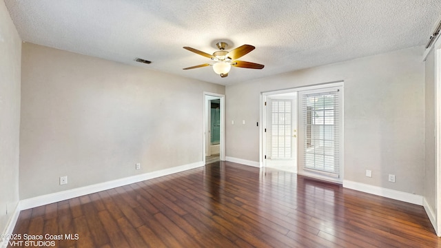 spare room with visible vents, wood finished floors, a ceiling fan, and a textured ceiling