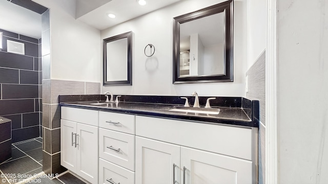full bath featuring double vanity, tile walls, walk in shower, and a sink