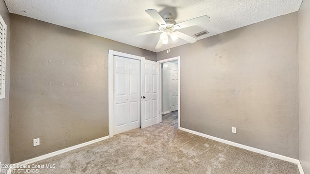 unfurnished bedroom featuring a textured ceiling, visible vents, a closet, and carpet floors
