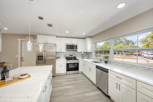 kitchen featuring a sink, visible vents, backsplash, white cabinets, and appliances with stainless steel finishes