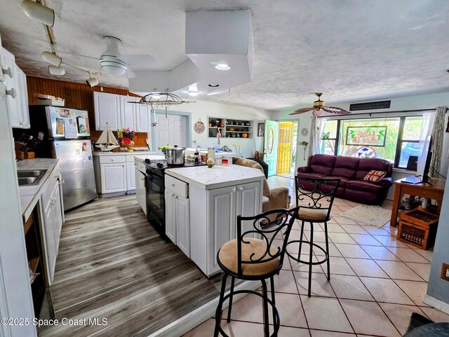 305 Harrison Ave, Cape Canaveral, FL 32920 - kitchen with a ceiling fan, white cabinetry, a kitchen island, black range with electric cooktop, and tile countertops