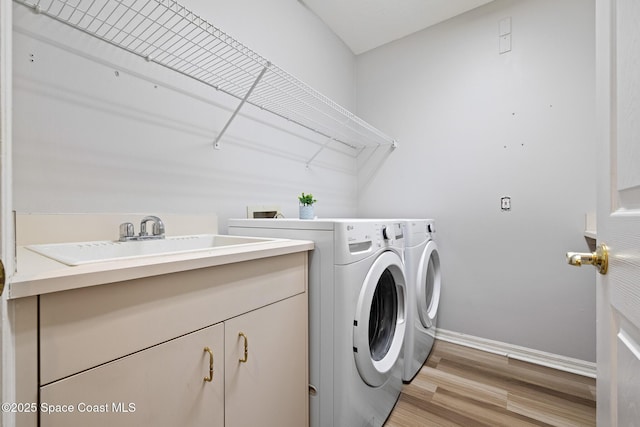 4800 Solitary Dr, Rockledge, FL 32955 - washroom featuring light wood-style flooring, washer and dryer, cabinet space, a sink, and baseboards