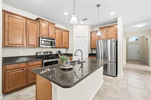 3624 Sansome Cir, Melbourne, FL 32940 - kitchen featuring stainless steel appliances, a sink, brown cabinets, hanging light fixtures, and a kitchen island with sink