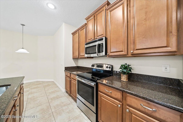 3624 Sansome Cir, Melbourne, FL 32940 - kitchen with stainless steel appliances, brown cabinetry, dark stone counters, pendant lighting, and a textured ceiling