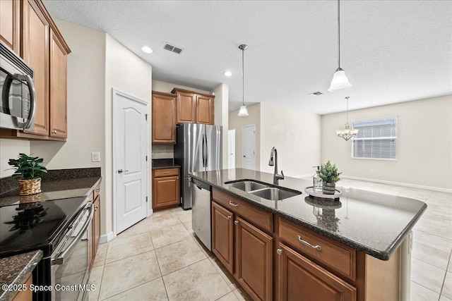 3624 Sansome Cir, Melbourne, FL 32940 - kitchen featuring a sink, stainless steel appliances, brown cabinets, dark stone counters, and a kitchen island with sink