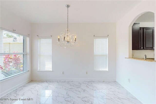 115 Briarcliff Cir, Sebastian, FL 32958 - unfurnished dining area with an inviting chandelier, arched walkways, marble finish floor, and a wealth of natural light