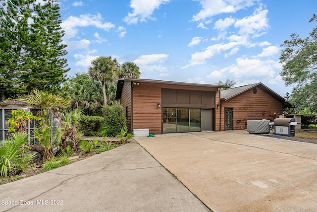 rear view of house with a patio, cooling unit, and driveway