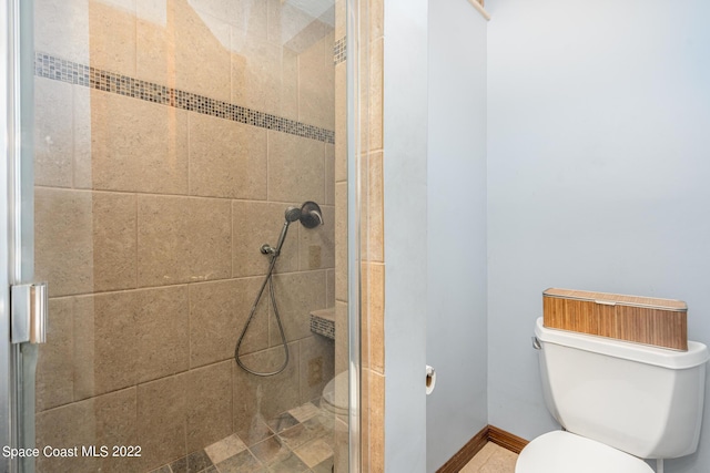 bathroom featuring toilet, a shower stall, and baseboards