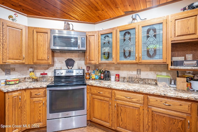 kitchen with stainless steel appliances, backsplash, crown molding, and light stone counters