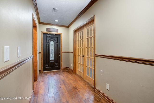 foyer with hardwood / wood-style floors, visible vents, ornamental molding, and french doors