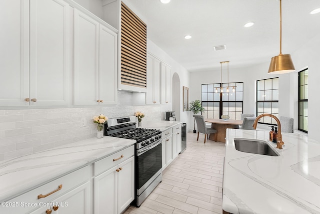 8048 Gullen Dr, Melbourne, FL 32940 - kitchen with decorative backsplash, stainless steel gas range, ventilation hood, white cabinetry, and a sink