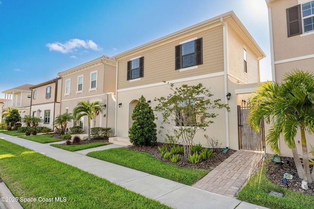 8048 Gullen Dr, Melbourne, FL 32940 - multi unit property featuring a gate, a front lawn, stucco siding, and a residential view