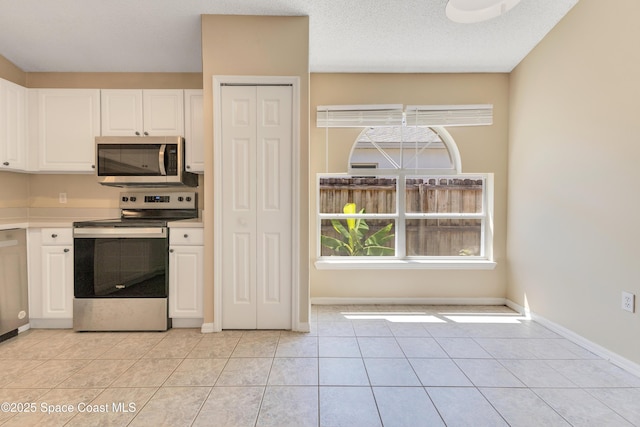 kitchen with white cabinetry, appliances with stainless steel finishes, light countertops, baseboards, and light tile patterned flooring