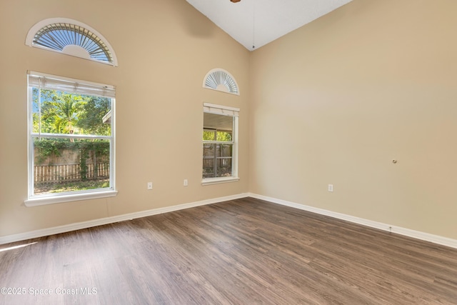 empty room featuring wood finished floors, a ceiling fan, high vaulted ceiling, and baseboards