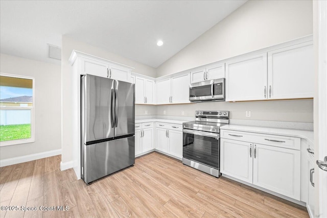 1204 Captiva Island Cir SW, Palm Bay, FL 32908 - kitchen featuring appliances with stainless steel finishes, light countertops, light wood-style flooring, lofted ceiling, and white cabinets