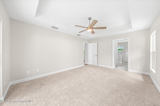 1204 Captiva Island Cir SW, Palm Bay, FL 32908 - unfurnished bedroom with a raised ceiling, light carpet, baseboards, ensuite bath, and a ceiling fan