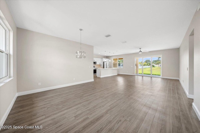 1035 Captiva Island Cir SW, Palm Bay, FL 32908 - unfurnished living room with wood finished floors, ceiling fan, baseboards, and a chandelier