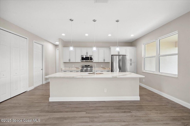 1035 Captiva Island Cir SW, Palm Bay, FL 32908 - kitchen with stainless steel appliances, white cabinets, a kitchen island with sink, light wood-style floors, and recessed lighting