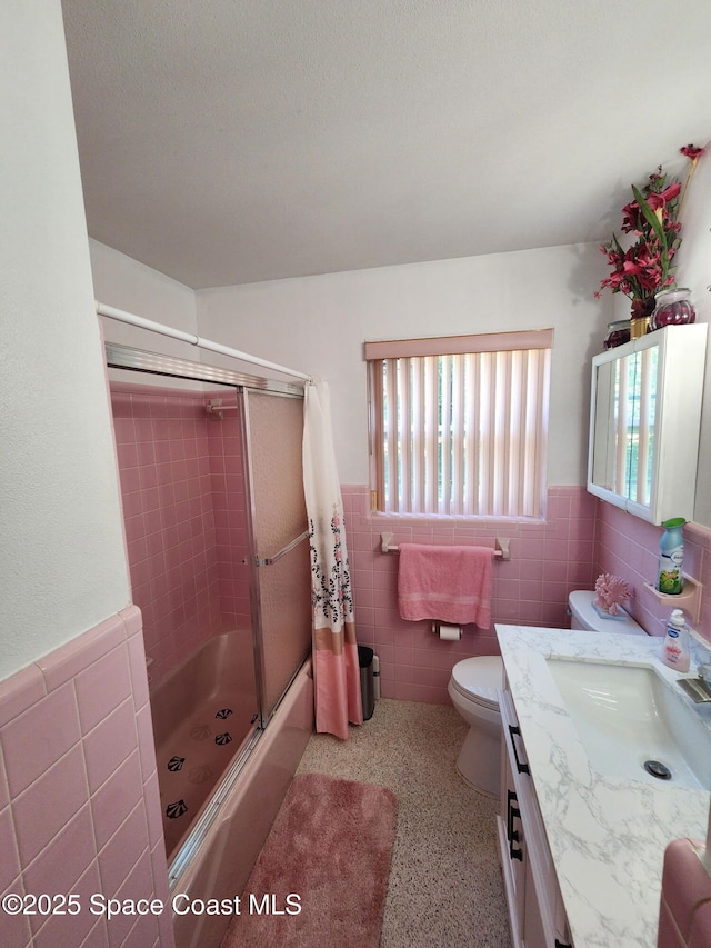 full bath featuring tile walls, plenty of natural light, a wainscoted wall, toilet, and vanity