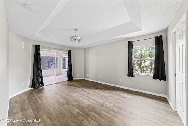 unfurnished bedroom with access to exterior, multiple windows, wood finished floors, and a textured ceiling