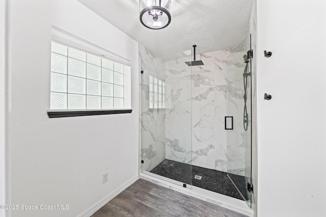 full bathroom with a marble finish shower, baseboards, a textured ceiling, and wood finished floors
