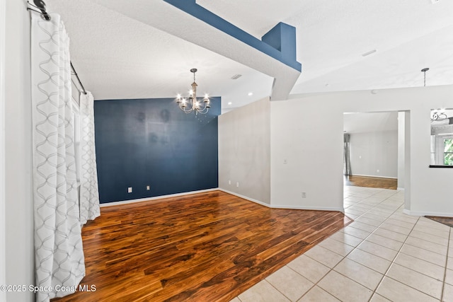 spare room with a chandelier, wood finished floors, and baseboards