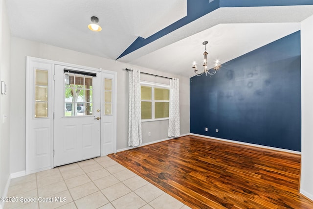entryway featuring a chandelier, light tile patterned floors, and baseboards