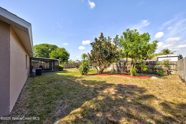 view of yard with a fenced backyard, a sunroom, and cooling unit