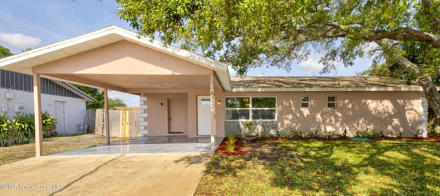 view of front of property with a front lawn, fence, stucco siding, concrete driveway, and a carport