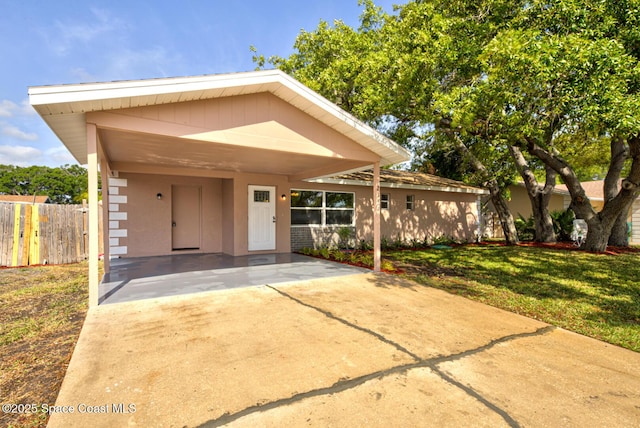 view of front facade with an attached carport, fence, and a front lawn